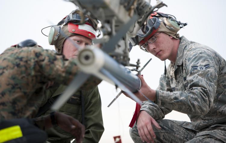 An Airman works alongside Marines to assist with loading munitions. Photo Credit: US Air Force/Senior Airman Armando A. Schwier-Morales.
